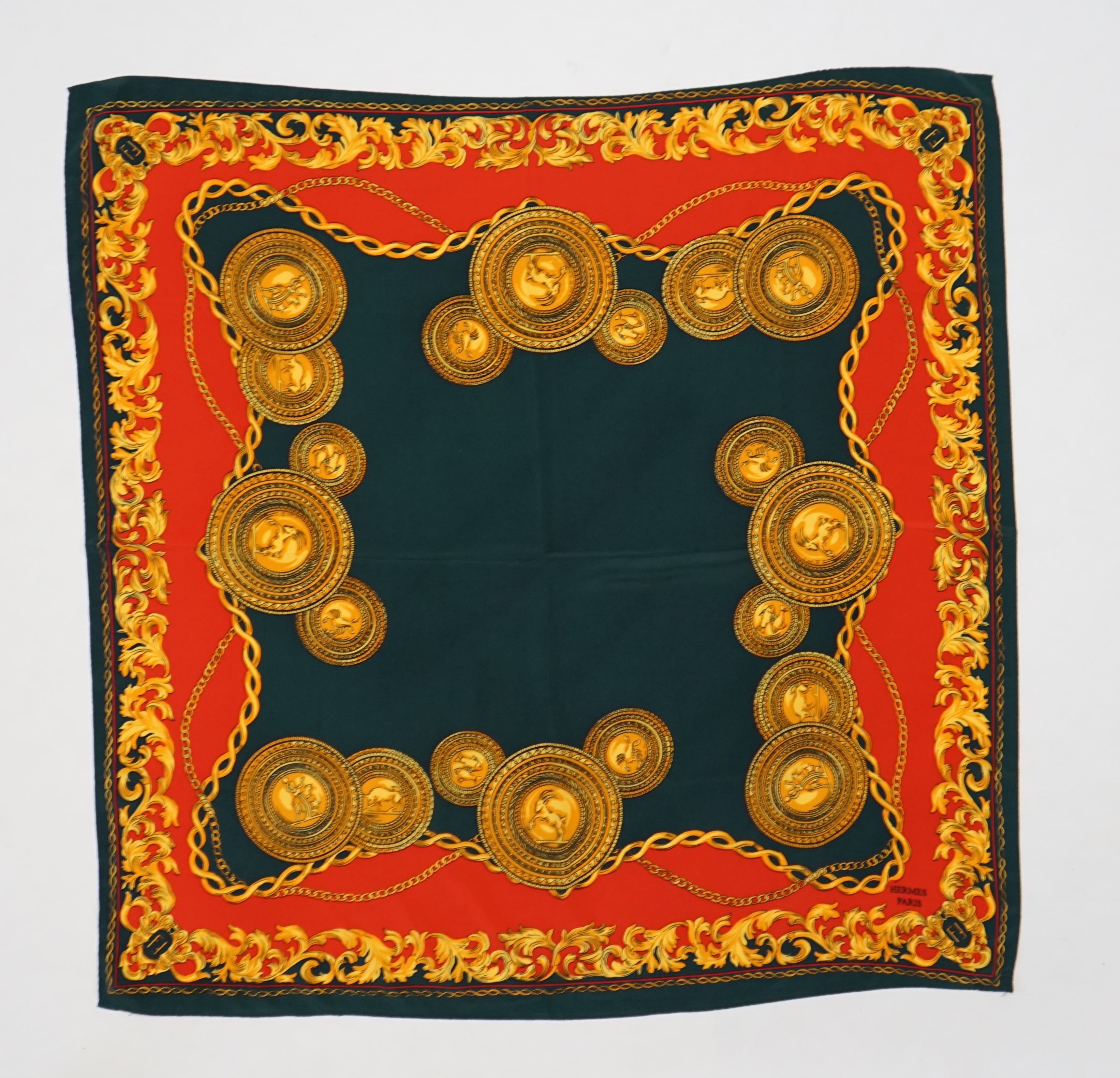 A Hermès silk scarf decorated with gold zodiac sign animals and hybrids, gold foliage and chain design around the edges, 90 x 84cm